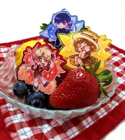 A photo of three keychains sitting in a bowl of strawberries, blueberries, and lemon. Each keychain is of one of the Lupinrangers printed on coloured acrylic, respective to their ranger colours.
